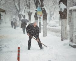 Sunday. Aman shoveling the snow on the street